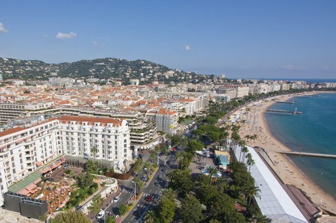 Vue aérienne de la plage et de la ville de Cannes Croisette avec ses bâtiments blancs et sa mer bleue.