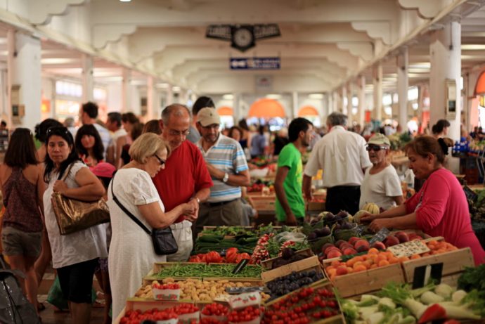 Fruits, légumes, fromages, herbes aromatiques disposés sur un marché alimentaire très fréquenté à Cannes.