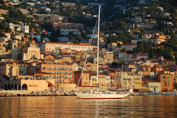 A boat at sunset at the port of Villefranche, with pretty coloured buildings in the background