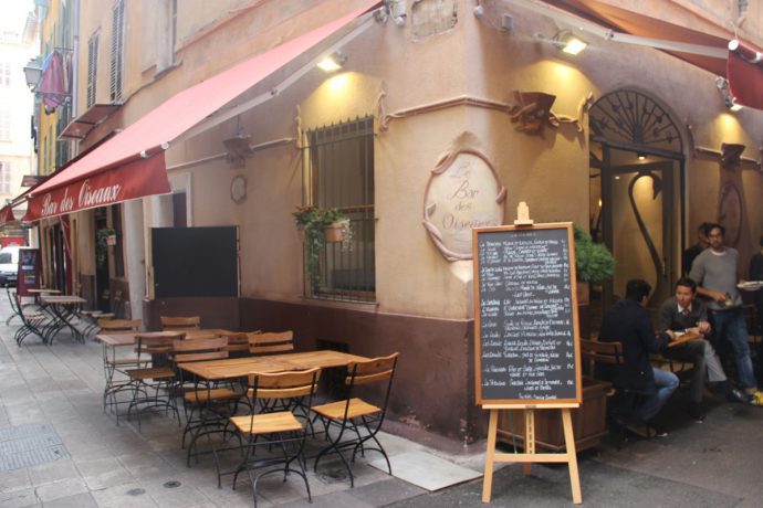Bar en terrasse sur un coin avec des chaises et des tables dans la vieille ville de Nice.